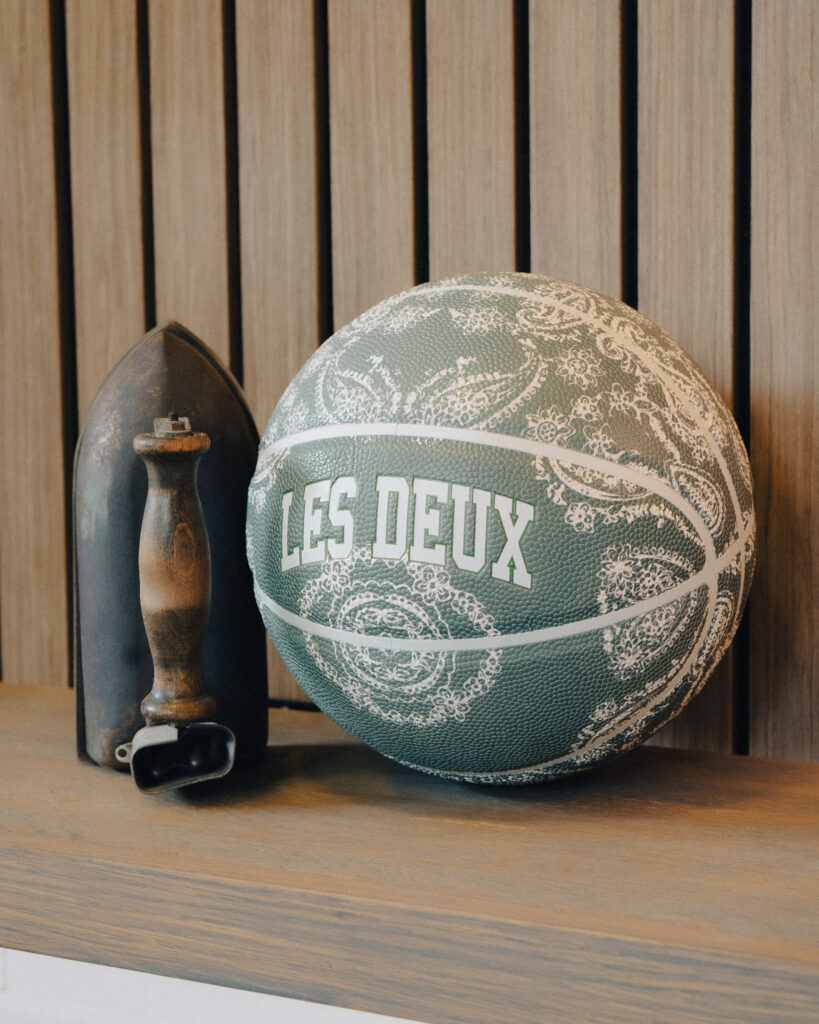 An image of a basketball propped against a vintage steaming iron on a shelf.